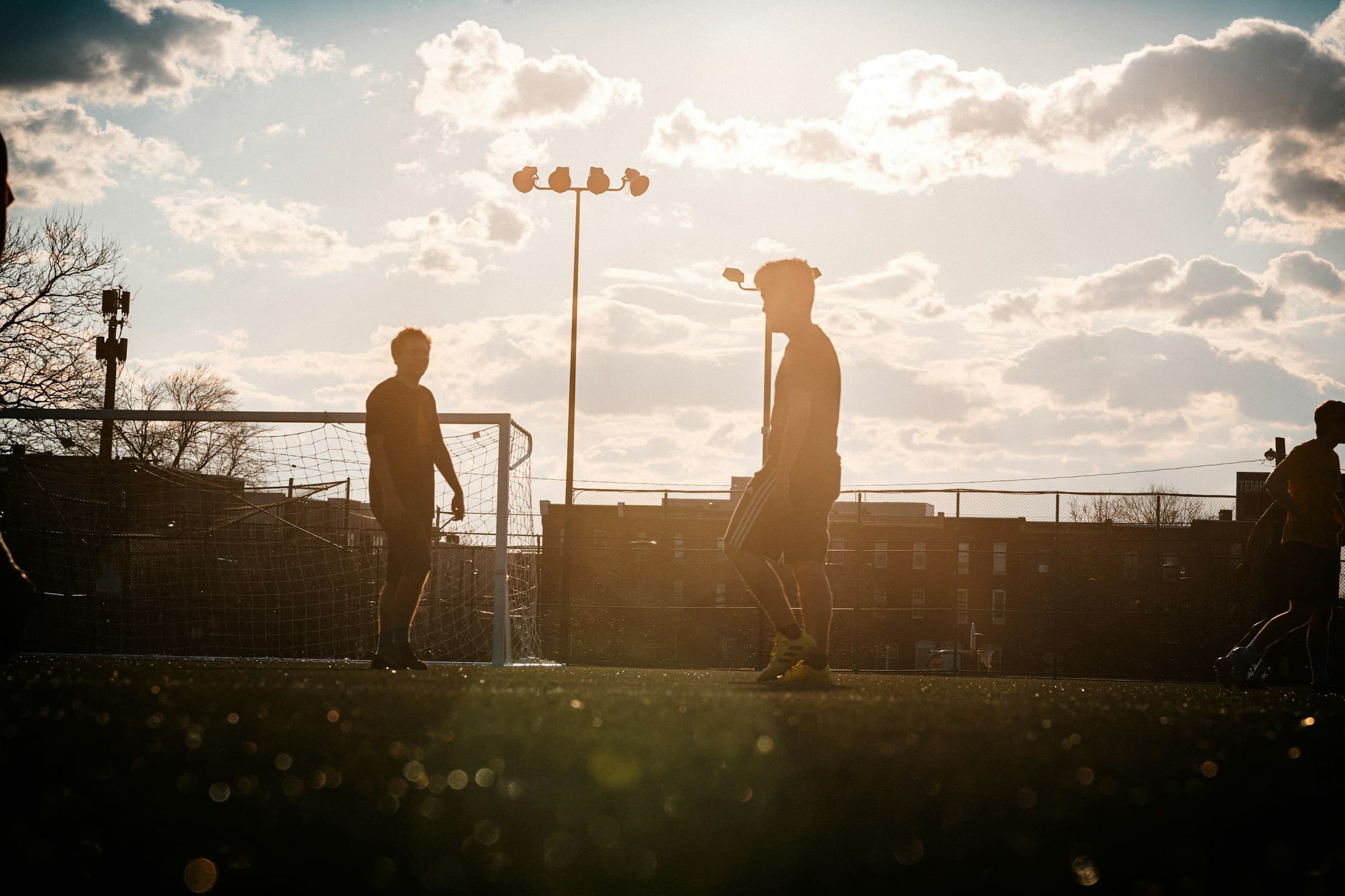 Soccer players beside a goal in the evening sun